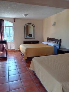 a hotel room with two beds and a mirror at Hotel Los Arcos in Tlalpujahua de Rayón