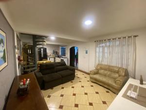a living room with two couches and a kitchen at Espaço Sol in Peruíbe