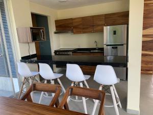 a kitchen with a bar with white stools in it at Aqua Reef Condos Sayulita Apt 2 in Sayulita