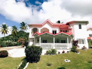 a pink house with a green yard at Krystal Apartment in Grande Rivière