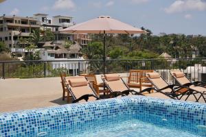 a swimming pool with chairs and an umbrella next to a pool at Aqua Reef Condos Sayulita Apt 2 in Sayulita
