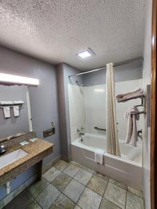 a bathroom with a tub and a shower and a sink at WESTERN MOTEl in Lucedale