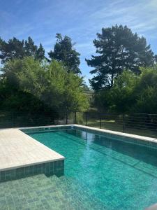 a swimming pool with blue water in a yard at Cabañas Punto Prana in Tandil +19 photos