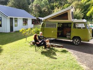 Twee mensen zitten op stoelen voor een groene bestelwagen. bij Te Mata Lodge in Tapu
