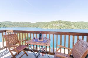 einen Tisch und Stühle auf einem Balkon mit Blick auf das Wasser in der Unterkunft Apartments Matana Chano in Polače