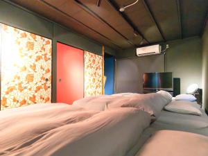 a bedroom with a bed with white sheets and a tv at Rino-Haku 03 in Anan