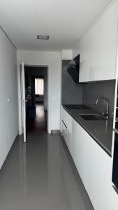 a kitchen with white cabinets and black counter tops at Casa DOURO-PORTO in Valbom