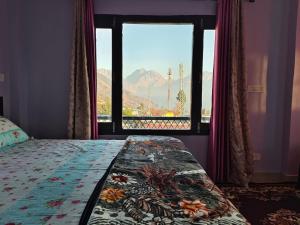 a bedroom with a window with a view of a mountain at Bilju Homestay in Munsyari