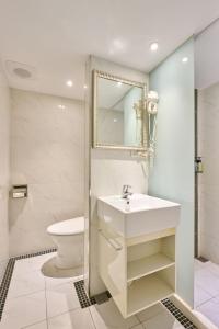 a white bathroom with a sink and a toilet at Golden Stone Hotel in Kaohsiung +31 photos