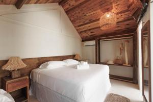 een slaapkamer met een wit bed en een houten plafond bij Casa do Amor Caraíva in Caraíva