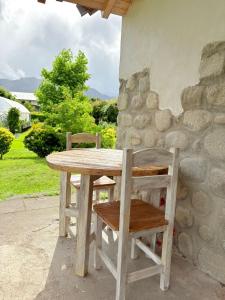 a table and two chairs sitting next to a stone wall at Complejo Los Saucos II in El Hoyo