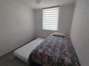 una piccola camera da letto con un letto con una coperta floreale di Departamento Salida Norte Temuco a Temuco