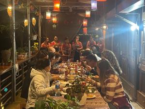 un gruppo di persone sedute a un lungo tavolo che mangiano cibo di OH Pu Luong Homestay a Hương Bá Thước