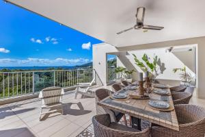 a dining room with a table and chairs on a balcony at Azure Sea Whitsunday Resort in Airlie Beach