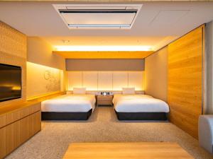 two beds in a hotel room with a tv and a room at AKEKURE Kyoto Shirakawa in Kyoto