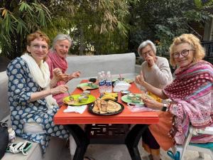 een groep vrouwen die rond een tafel eten bij Shankar Homestay in Hampi