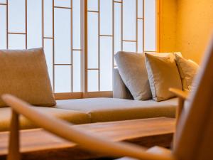 a couch sitting in front of a window with pillows at AKEKURE Kyoto Shirakawa in Kyoto