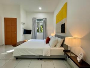 a bedroom with a large white bed and a window at Bloc Guesthouse in Pantai Cenang