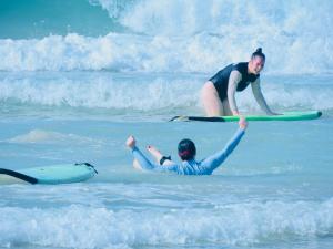 two people in the ocean with surfboards in the water at Nirvana Surf Retreat - Kabalana in Atadahewatugoda
