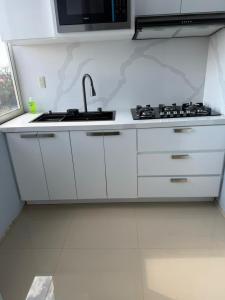 a white kitchen with a sink and a microwave at Cuarto Privado in Arandas +4 photos
