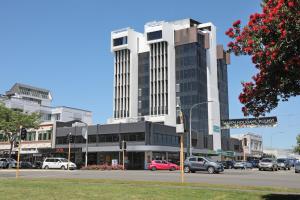 a large building with cars parked in front of a street at Ramada Encore by Wyndham Palmerston North in Palmerston North