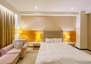 a bedroom with a large white bed and a couch at Jade Garden Hotel - 翠華會館 in Gukeng