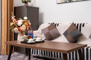 a coffee table in front of a couch with flowers at Nagomi Residence in Hanoi