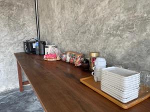 a wooden table with plates and other items on it at COCO Home 2 โคโค่โฮม เฟส 2 in Ban Mo Kaeng Taek