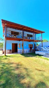 a large house with a balcony and a grass field at Paraíso Azul in Ilhéus