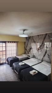 a room with three beds and a stone wall at Piso entero La Boca in Buenos Aires