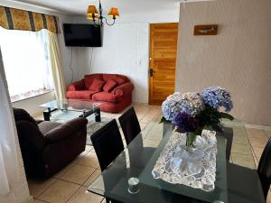 a living room with a table with a vase of flowers on it at Los Castaños Pucón in El Cerrillo