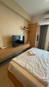 a bedroom with a bed and a flat screen tv at ANDERSON BENSON CONNECT PAKUWON MAll in Surabaya