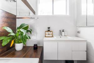 a white kitchen with a sink and a potted plant at The Unit Lennox Head in Lennox Head +6 photos