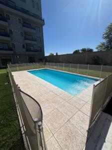 a swimming pool with a fence next to a building at Dalcar Apart in Río Cuarto