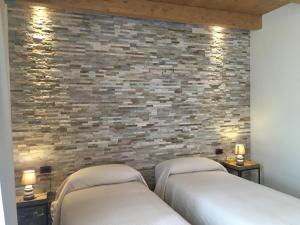 two beds in a room with a brick wall at Agriturismo da Mamma in Alba
