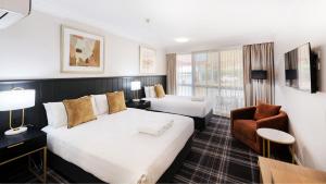 a hotel room with two beds and a chair at Dubbo RSL Club Motel in Dubbo +58 photos