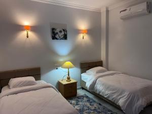 a bedroom with two beds and a lamp on a night stand at Spacious Luxury Nile-View Apartment on Upper Floor with Rooftop, Jacuzzi & BBQ ,Steps from Hilton Hotel in Luxor