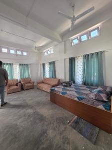 a bedroom with a bed and a couch and windows at The White House By Bhaskar Homestay in Dibrugarh
