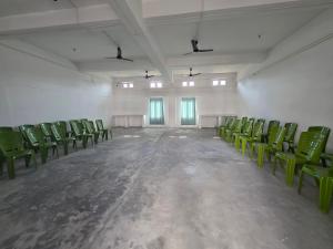 an empty room with green chairs and windows at The White House By Bhaskar Homestay in Dibrugarh