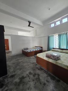 a large room with two beds and two windows at The White House By Bhaskar Homestay in Dibrugarh +3 photos