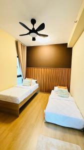 two beds in a room with a ceiling fan at Aisy Suite Splash Mania View in Bandar Gamuda Cove
