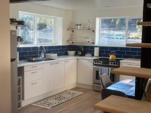 a kitchen with white cabinets and blue tiles at Modern barn by the creek in Evergreen