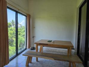 a table and bench in a room with a large window at Keramas Selukat Guest House in Keramas
