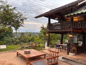een houten paviljoen met banken en tafels in een veld bij Baandindon Private Earthhouse Homestay in Mae Rim