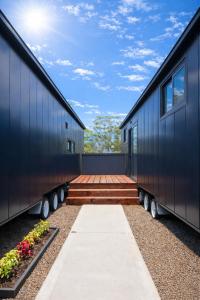 a black house with a walkway between two buildings at Tiny Home in Casula Station