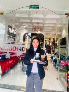 a woman holding a tray with a drink in a store at Diamond Hotel Sapa in Sapa