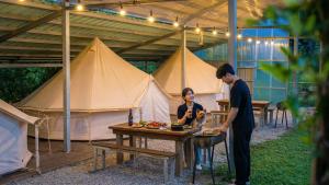 a man and a woman standing at a table in front of tents at Yangyang Slowstay Pension in Yangyang