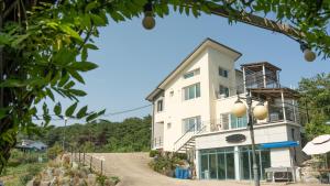 a white building on a hill with a tree at Yangyang Slowstay Pension in Yangyang