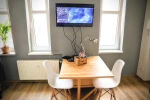 a dining room table with white chairs and a tv on the wall at Armonia Old Town in Poznań