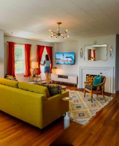 a woman standing in a living room with a yellow couch at Rye Motor Inn - Oceanfront, Walk to Beach in Rye +19 photos